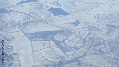 View from airplane window seat, snowy fields on the ground.