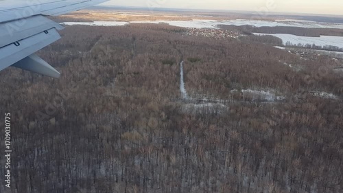 Plane flying over snowy forest, view from passenger window.