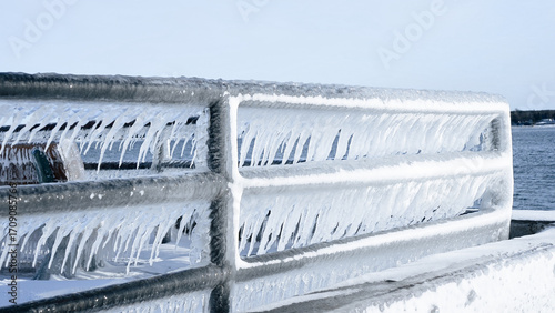 Beautiful Icicles Hanging from a Metal Railing Overlooking a Stunning Frozen Lake Scene
