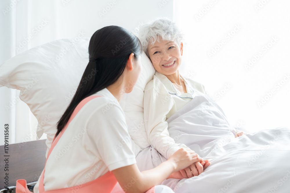 Obraz premium 高齢者を介護する若い女性介護士
