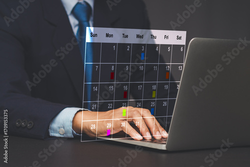 Businessman using laptop with digital calendar schedule.