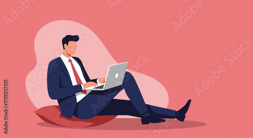 A focused businessman in a suit works diligently on his laptop, comfortably seated on the floor, showcasing flexible modern work arrangements.
