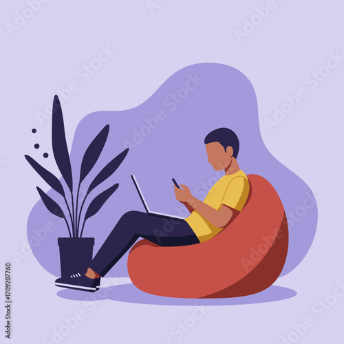 Young man relaxing on a beanbag chair, multitasking with a laptop and smartphone. Ideal for remote work, digital lifestyle, and casual productivity.