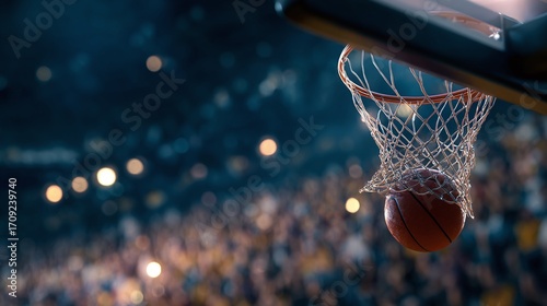 A close-up shot of a basketball passing through the net. The background is a blurred stadium crowd with spotlights, capturing the moment of a successful score.