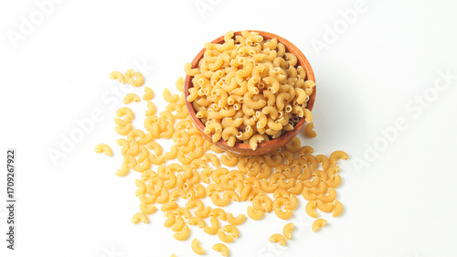 Tableau sur toile Curved macaroni pieces surround a wooden bowl of raw pasta on white background