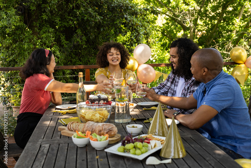 Toasting with wine glasses, friends celebrating and sharing festive meal outdoors