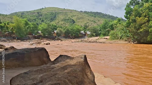 Muddy River Flowing Through Lush Green Valley with Mountain Backdrop
