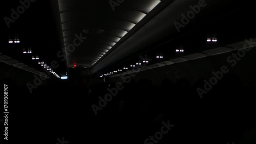 view inside airplane cabin full with passenger inside aircraft while traveling flying in night time flight while dime light down ready to landing, holiday aeroplane travel transportation