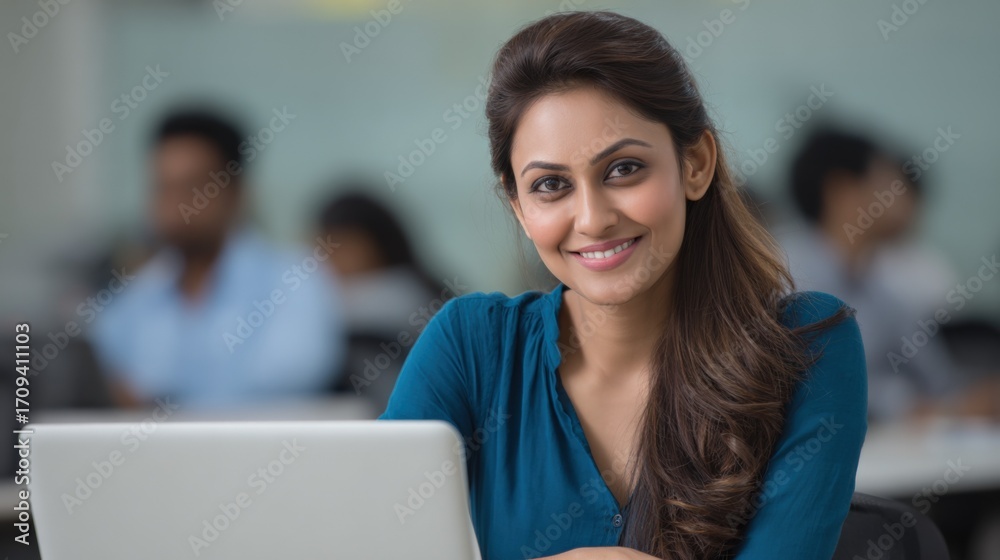 Fototapeta premium Smiling Indian Woman Working on Laptop in Office: Modern Workspace, Professional Portrait