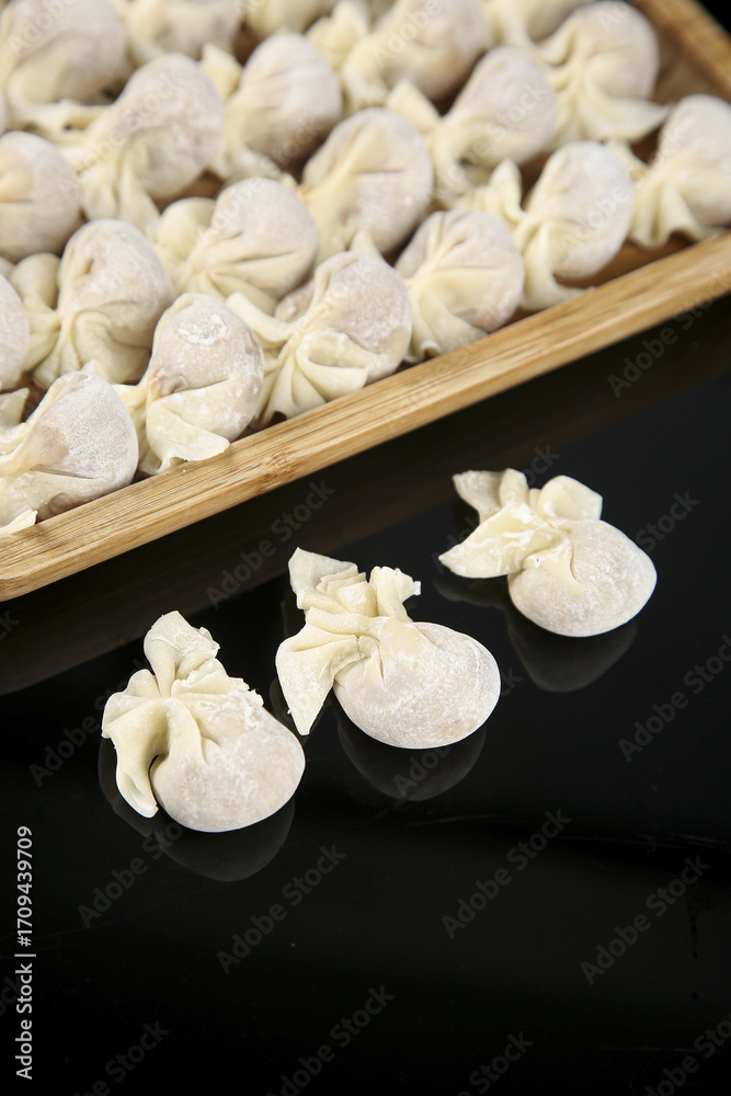 Obraz premium Fresh Wontons in Bamboo Steamer Basket Ready for Cooking Traditional Chinese Dumplings