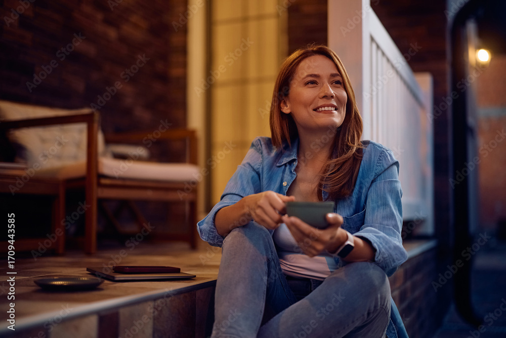 Obraz premium Happy woman day dreaming while drinking coffee on porch.