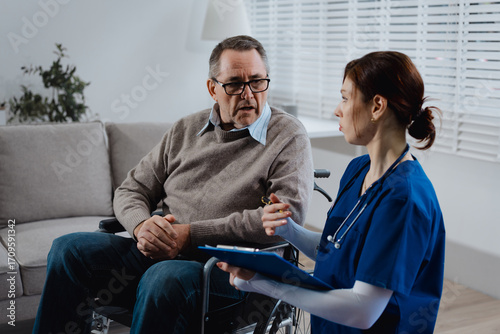 An elderly male patient in a wheelchair discusses neck pain with a young nurse taking notes in a comfortable patient room, focusing on medical consultation,nursing care, rehabilitation, and mobility