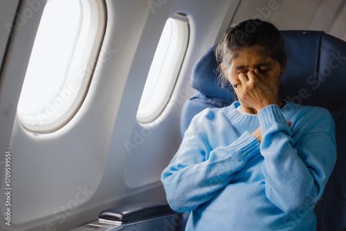 Fotografija An elderly Asian woman sits inside an airplane, suffering from dizziness, nausea
