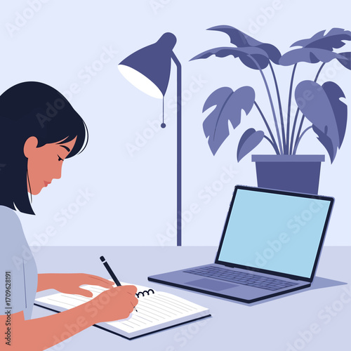 Woman working on a laptop and writing in a notebook at a desk with a lamp and a plant