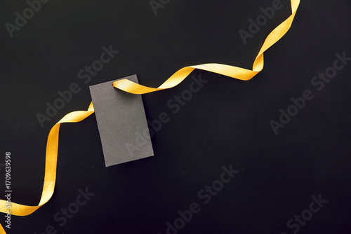 A black gift tag with a yellow ribbon on a dark background. Ideal for Black Friday sale promotions and marketing materials.