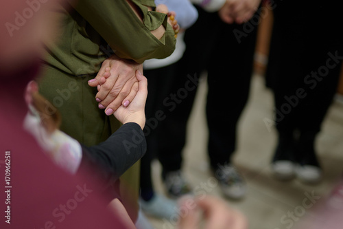 Close-up of a hand in a supporting gesture, surrounded by others, demonstrating support, unity, and care within a community