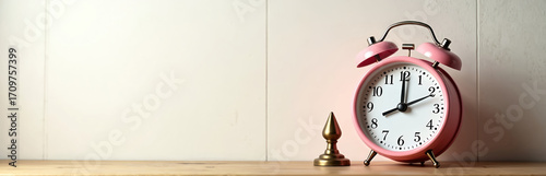 Charming pink retro alarm clock with classic vintage design. Old-fashioned horologe on shelf, evokes nostalgia, ideal home decor. Brass accent adds unique detail. Timepiece functions perfectly.