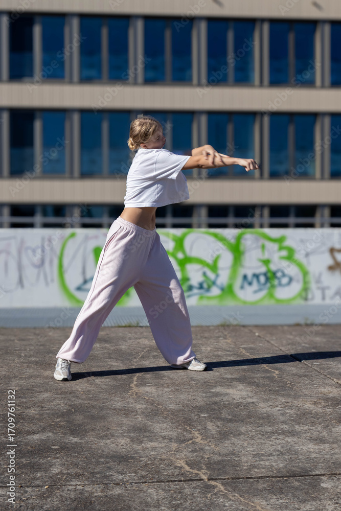 Fototapeta premium A young woman does dance exercises outdoors