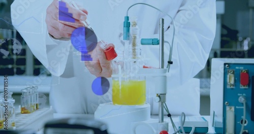 Scientist wearing lab coat holding test tube above yellow beaker on stir plate at bench, cables