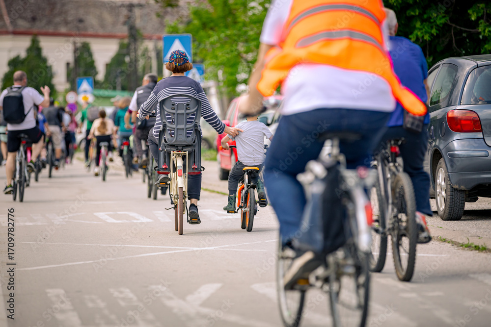 Fototapeta premium Children among group of cyclists on city road, street, asphalt