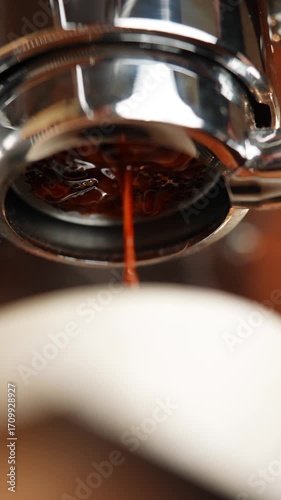 A coffee machine with a coffee filter in it is being used to make coffee. The coffee machine is silver and has a shiny appearance