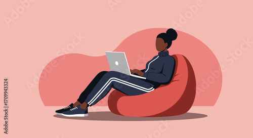 A focused Black woman wearing a casual tracksuit works on her laptop, comfortably seated on a red bean bag chair within a modern, relaxed home environment.