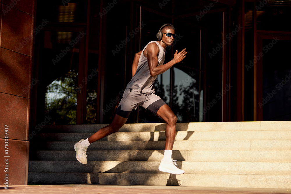 Fototapeta premium Athletic man running outdoors wearing headphones for training and fitness