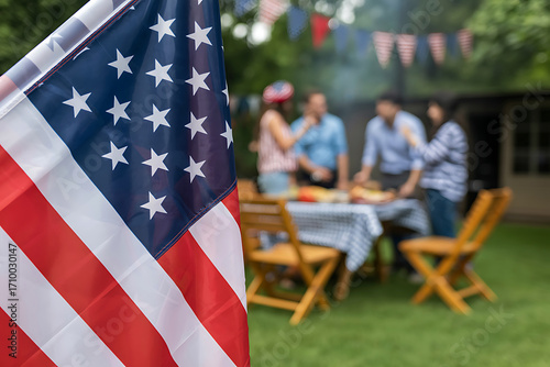 American flag in foreground celebrating a backyard barbecue with family and friends outdoors