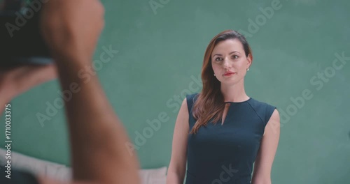 Photographer raising camera to frame model in green screen studio