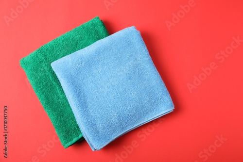 Bright terry towels on red background, top view. Space for text