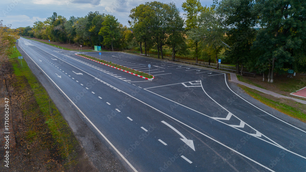 Fototapeta premium Drone aerial view new asphalt road in autumn on a cloudy day, road markings