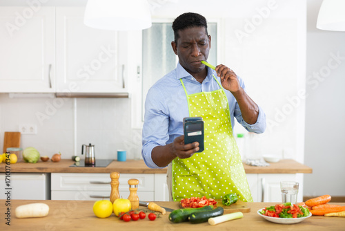 Man using smartphone while preparing food at home