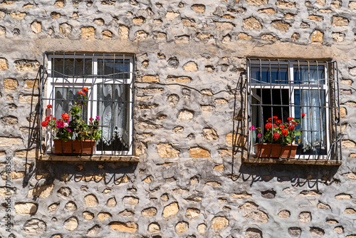 Stylish house windows with colorful flowers and stone walls, a sweet house with two windows