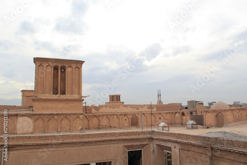 Traditional wind towers in Yazd's historic mud-brick alley, showcasing ancient Persian architecture under a clear blue sky. Ideal for travel, culture, and history themes.