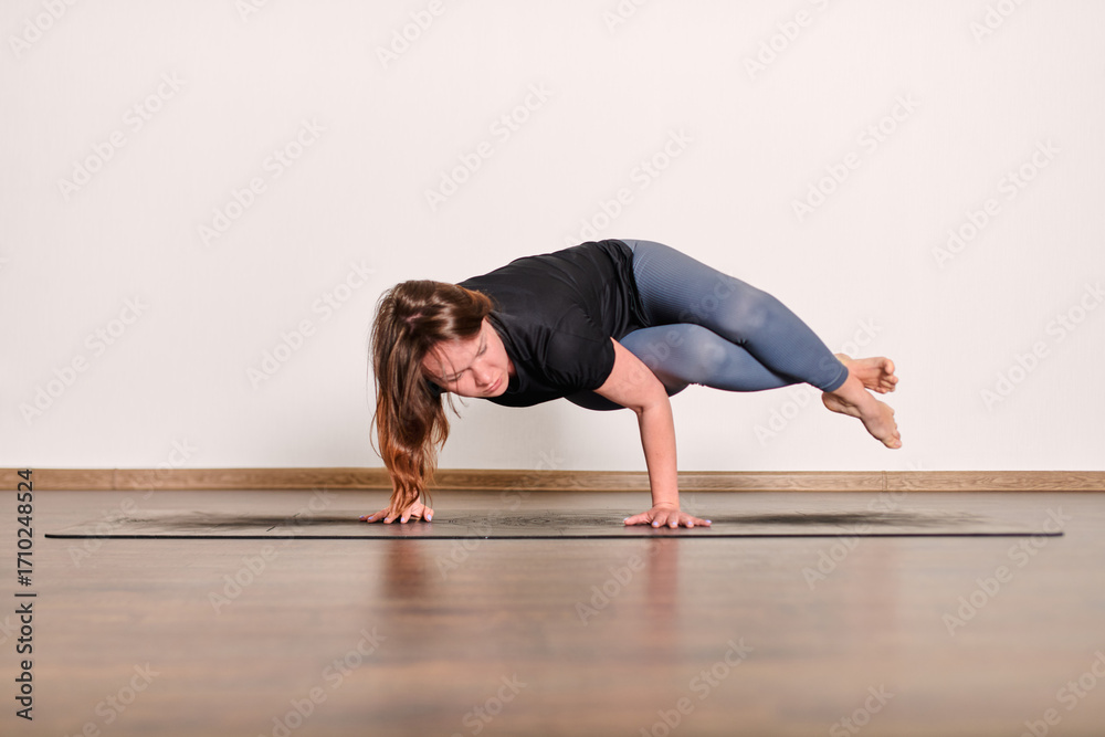 Naklejka premium Focused yoga pose on wooden floor