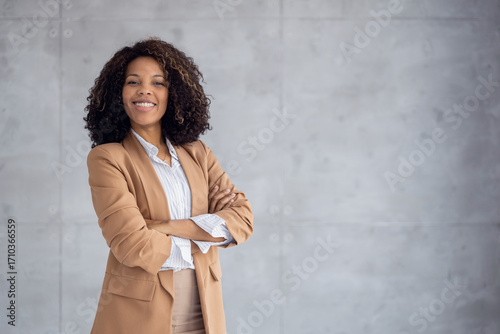 Confident businesswoman standing in a modern office with a smile while crossing her arms