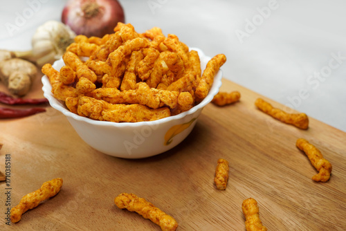 Delicious India favorite snack kurkure crunchy corn sticks served in a bowl, on white background. Indian tea snacks concepts.