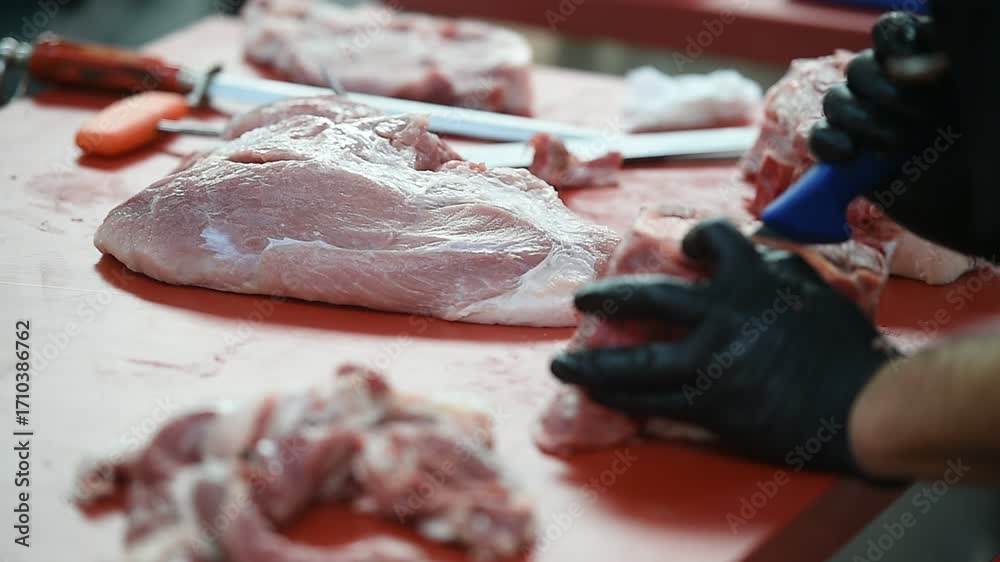 Butcher cutting pork primal meat cuts, such as the leg, loin, rack, and ...