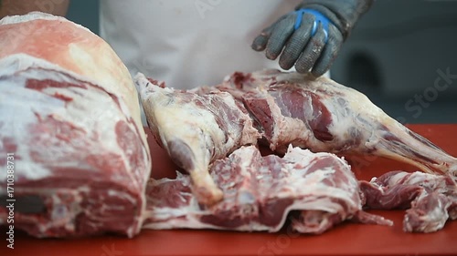 Butcher cutting pork primal meat cuts, such as the leg, loin, rack, and shoulder