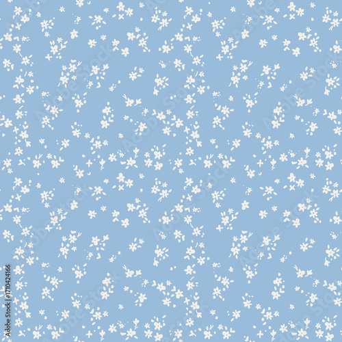 Simple ditsy floral seamless pattern with tiny white flowers on a blue background. Cute and delicate vintage print for textile, fabric, or wallpaper. Spring cottagecore style design.