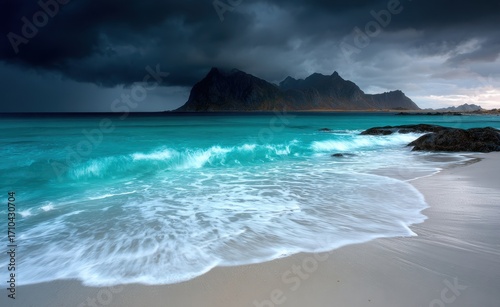 White sand beach, turquoise water with black mountains in the background, stormy weather