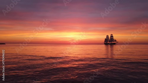 Dramatic sunset over calm ocean with sailboat