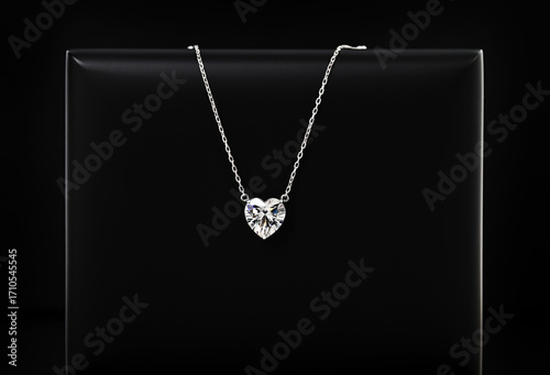 A necklace with a heart pendant is on a black record