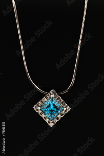 A blue diamond necklace sits on a black surface