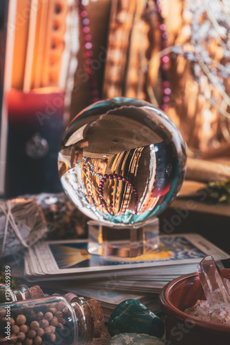 Mystical crystal ball resting on tarot cards surrounded by gemstones, herbs, and magical altar tools for divination and spiritual rituals.