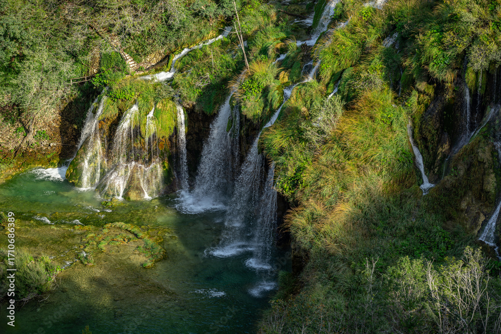 Obraz premium Waterfall in the Plitvice Lakes in Croatia. The waterfalls in forest. Summer view of beautiful waterfalls and clear lake. Plitvice Lakes National Park, Croatia. Summer nature landscape.