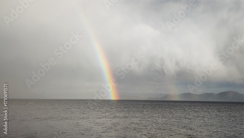 double rainbow arc above sea level ocean horizon dramatic sky weather