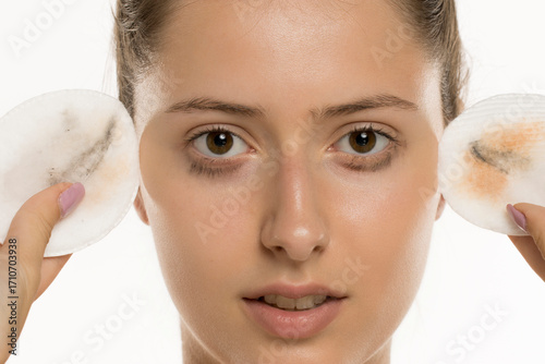 Studio shot of young woman closeup face holding used cotton pads with removed makeup on white background.
