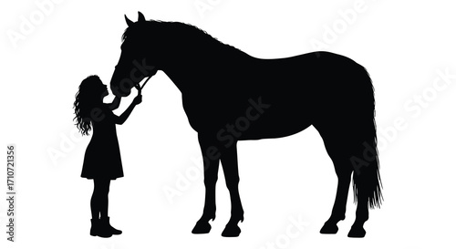 Silhouette of a young girl gently feeding a large black horse