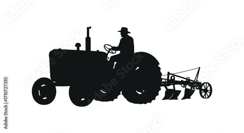 A silhouette of a farmer driving an antique tractor in a field